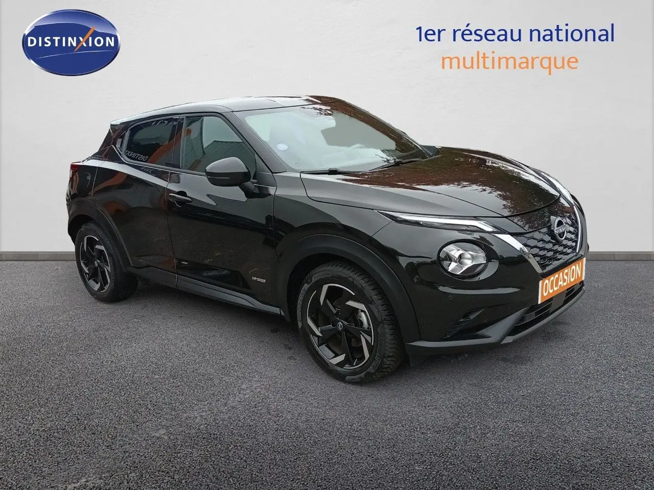 Nissan Juke Hybrid noir métal en 3/4 avant droit, avec jantes noires et calandre distinctive V-Motion.
