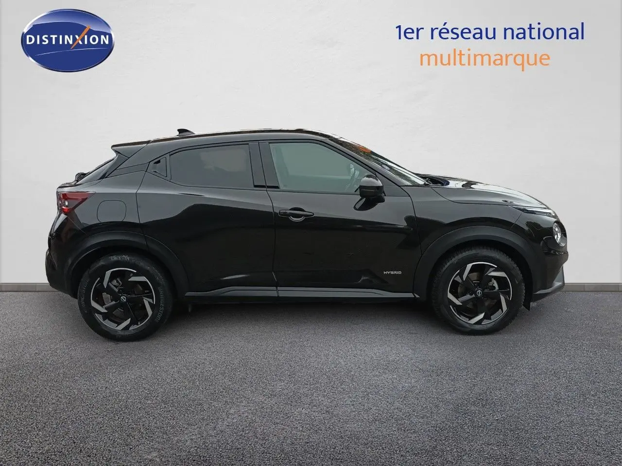Profil droit du Nissan Juke Hybrid 143ch Business+ 2024 en noir métal avec jantes noires et détails hybrides visibles.