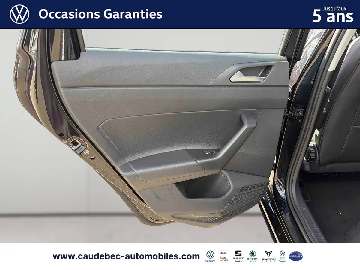 Vue rapprochée de la porte arrière gauche ouverte d’une Volkswagen Polo noire intense nacrée, montrant la garniture intérieure grise.
