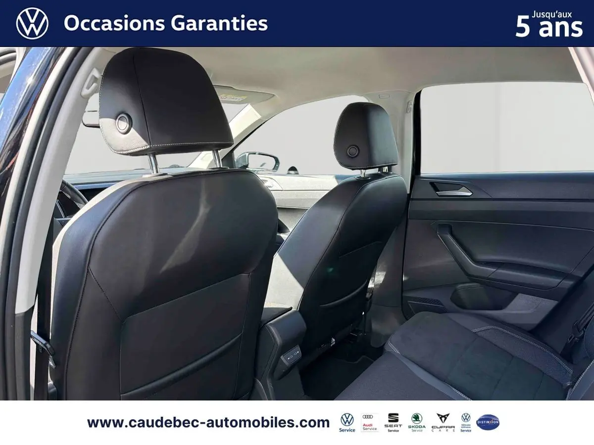 Vue intérieure arrière montrant les sièges avant en cuir noir et la banquette arrière tissu foncé d'une Volkswagen Polo 2025.