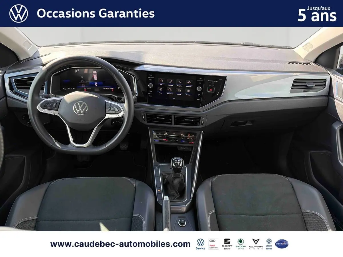 Vue intérieure avant de la Volkswagen Polo 2025, tableau de bord noir avec volant cuir multifonctions et écran tactile central.