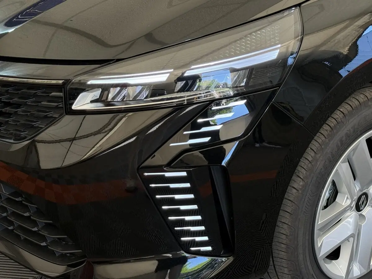 Gros plan sur l'avant droit noir de la Renault Clio 2025, mettant en valeur ses phares LED et la jante alu distinctive.