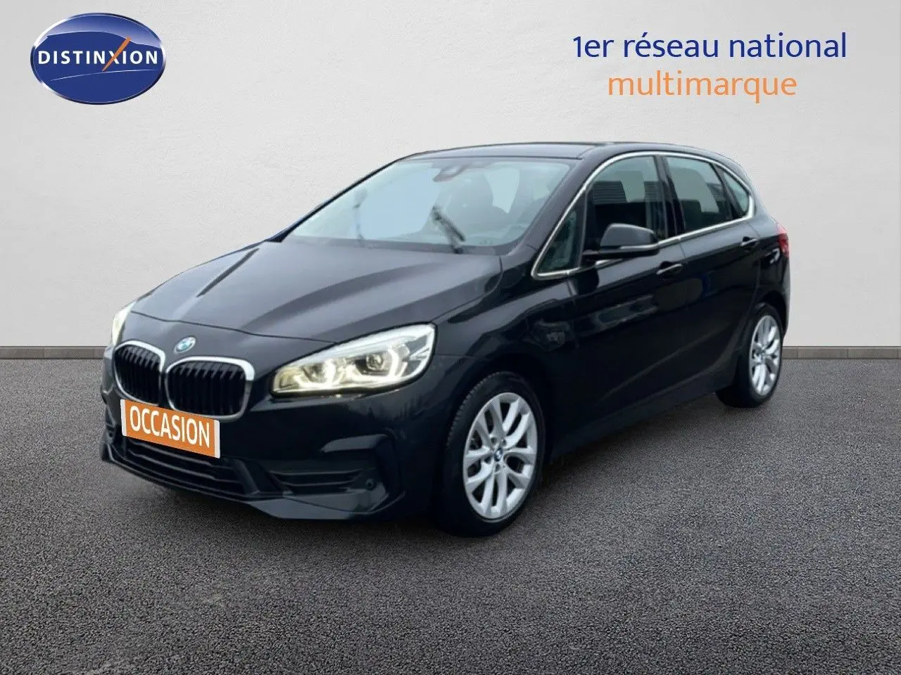 BMW Série 2 Active Tourer noir saphir métal vue 3/4 avant droit avec phares allumés sur fond neutre.