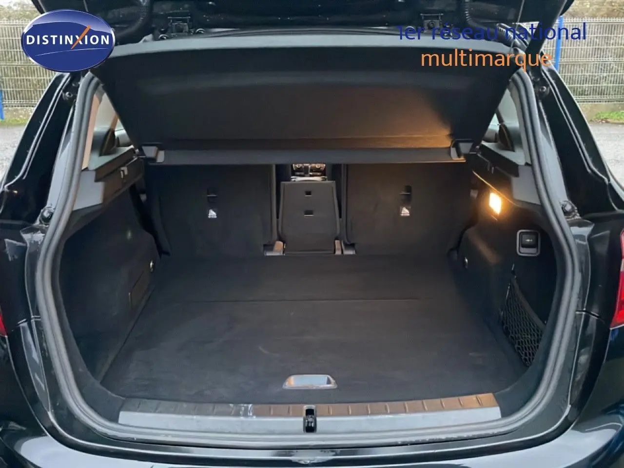 Coffre ouvert vu de l'arrière d'une BMW Série 2 Active Tourer noir saphir métal, intérieur spacieux et éclairage latéral allumé.