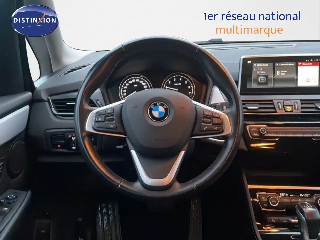 Vue intérieure centrée sur le volant cuir noir d'une BMW Série 2 Active Tourer 225XE avec tableau de bord et écran multimédia.