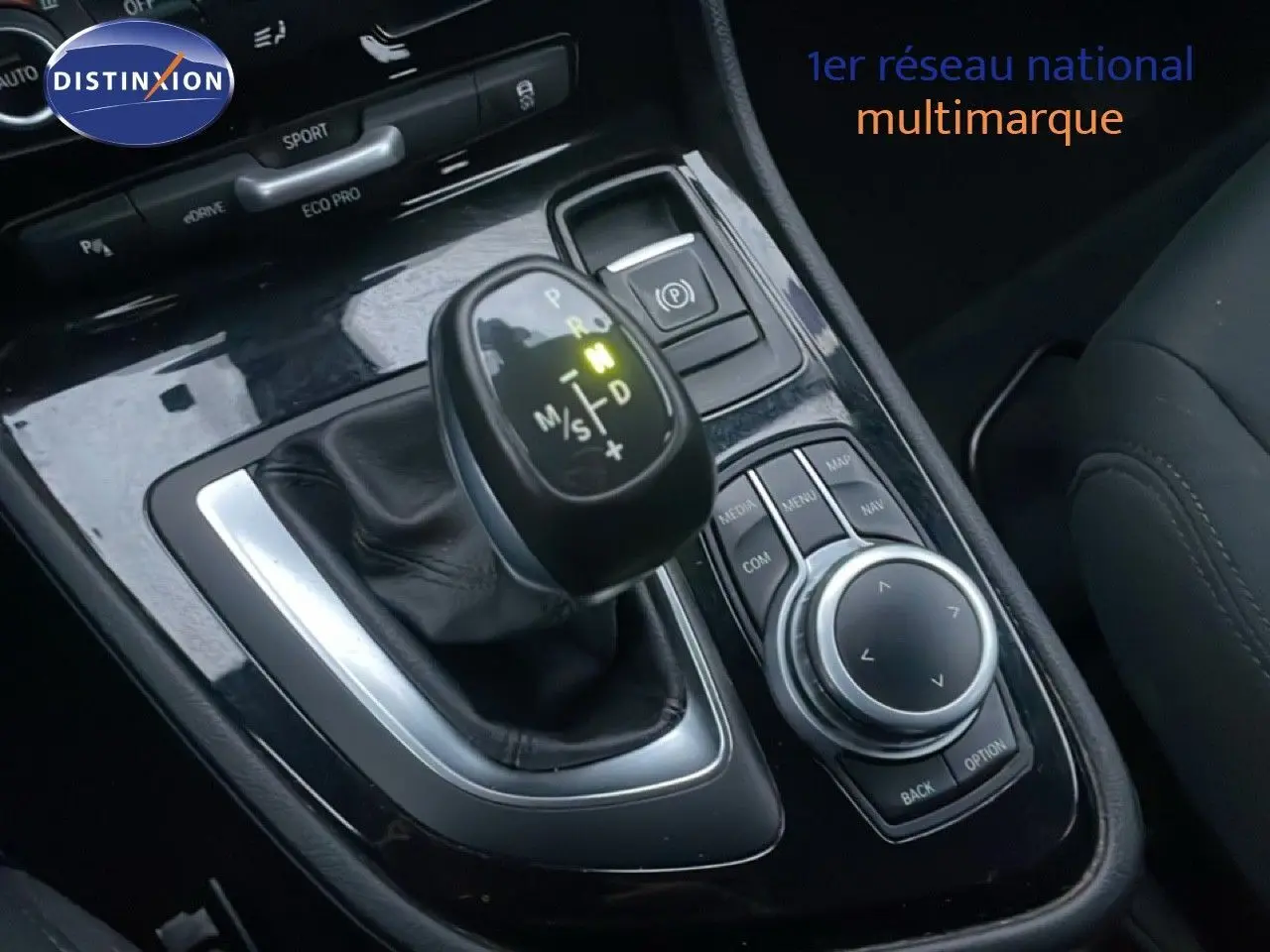 Gros plan sur la console centrale de la BMW Série 2 Active Tourer noire, avec levier de vitesse et commandes multimédia visibles.
