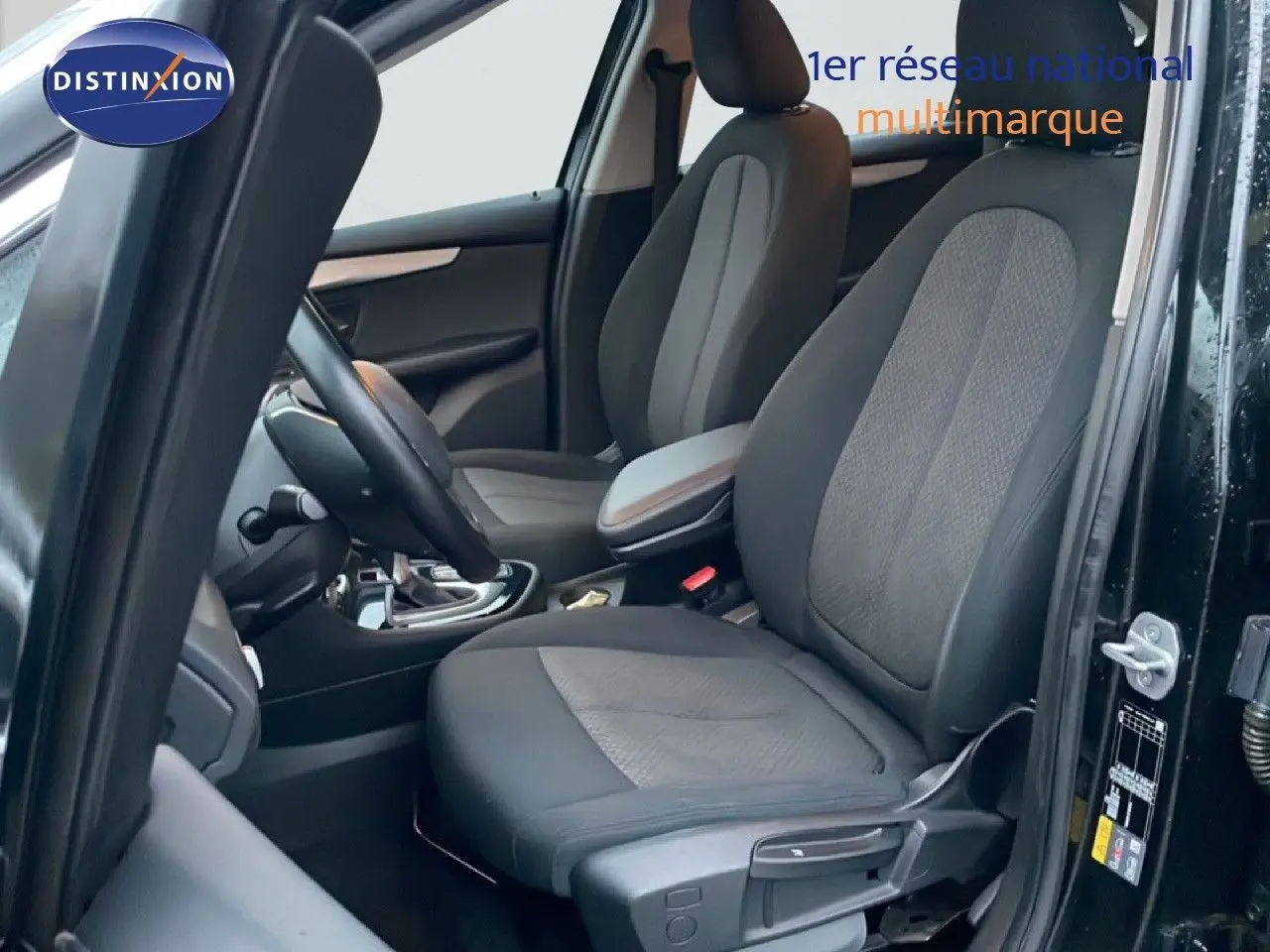 Vue intérieure côté conducteur d'une BMW Série 2 Active Tourer noire, montrant les sièges avant en tissu et cuir.