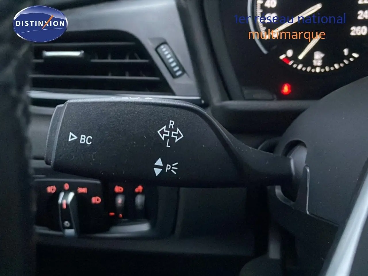 Gros plan sur la commande de clignotants à gauche du volant dans l’habitacle noir d’une BMW Série 2 Active Tourer 225XE.
