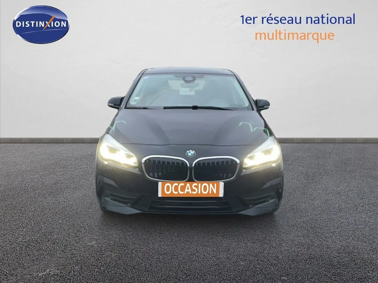 Vue frontale d'une BMW Série 2 Active Tourer noire avec phares allumés sur fond neutre.