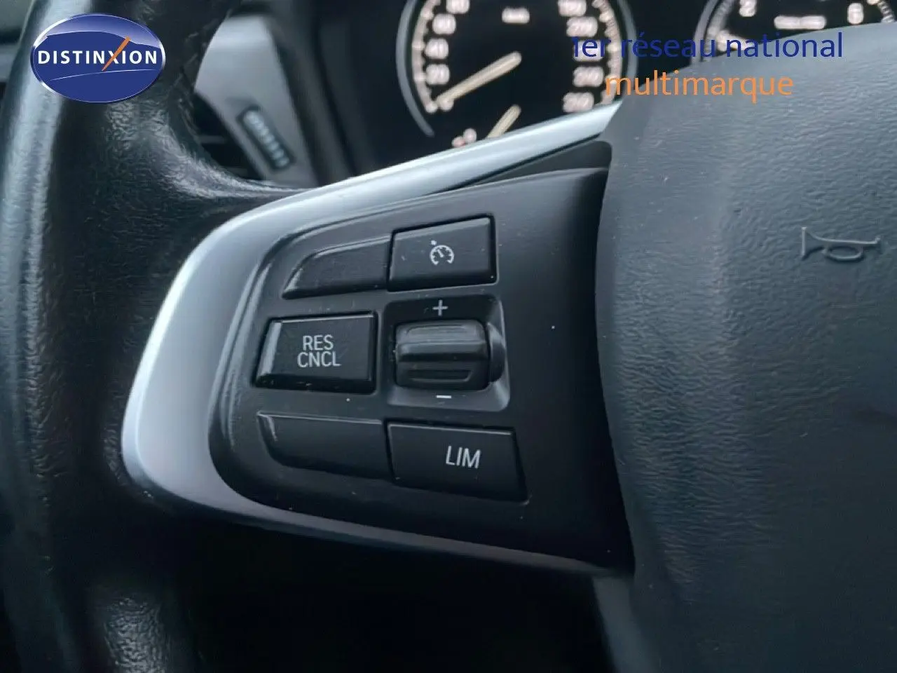 Gros plan sur les commandes de régulateur de vitesse au volant d'une BMW Série 2 Active Tourer noir saphir métal.
