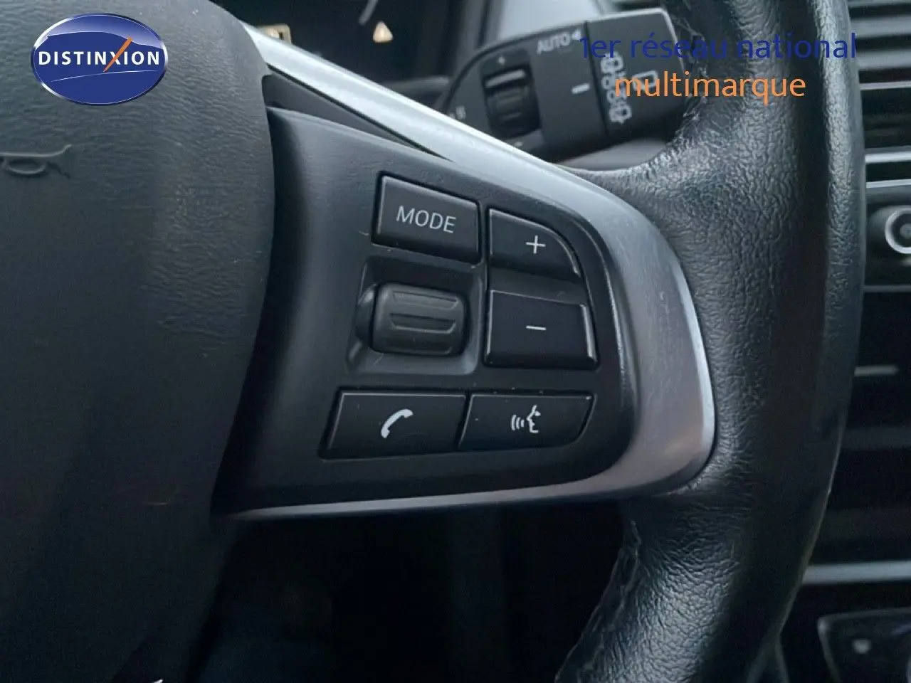 Gros plan sur les commandes au volant en cuir noir d'une BMW Série 2 Active Tourer 225XE 2021, finition Business Design.
