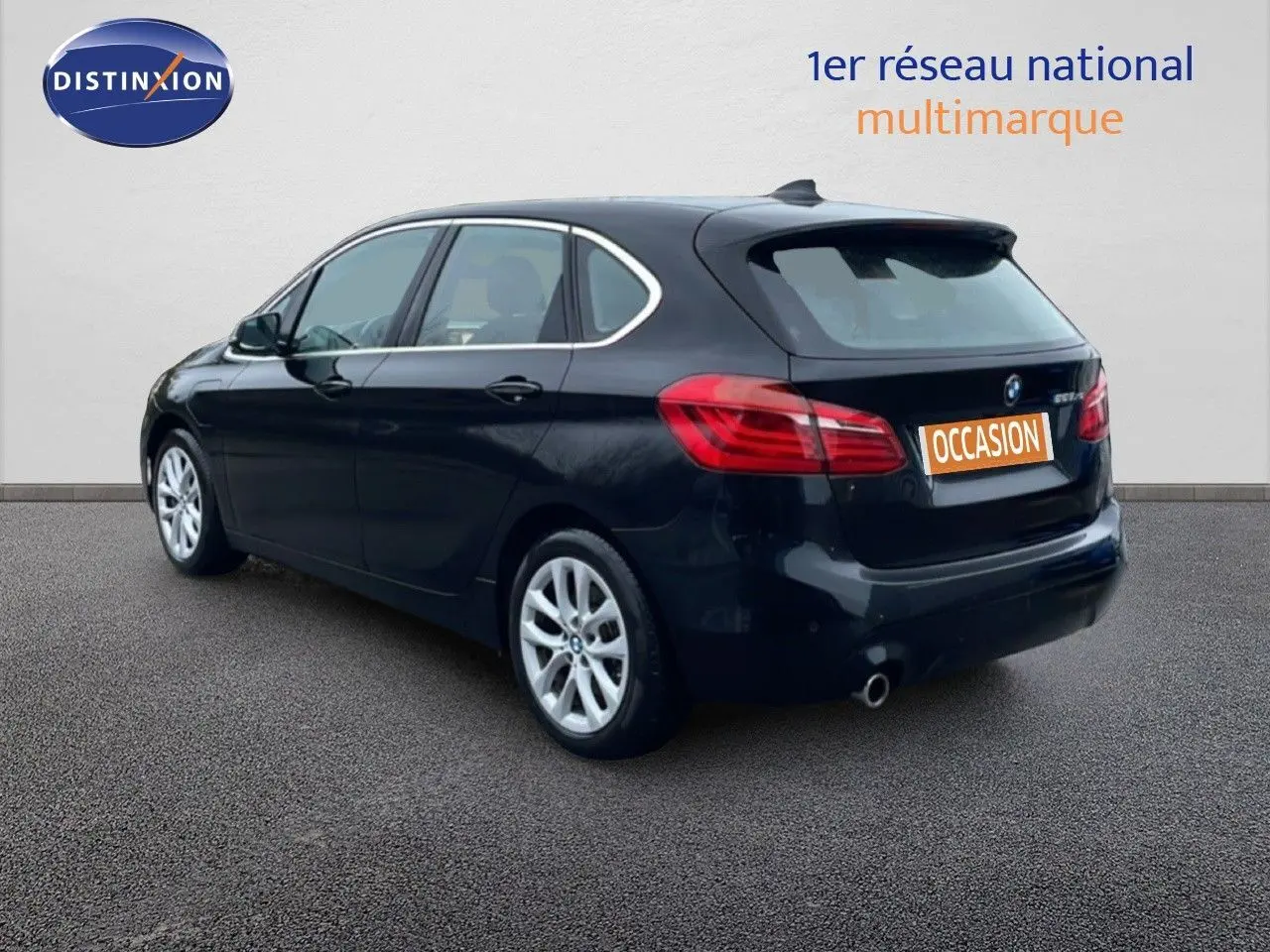 BMW Série 2 Active Tourer noir saphir métal en 3/4 arrière droit, avec jantes argentées et feux arrière visibles.