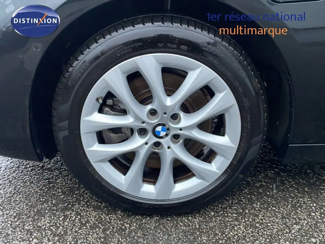 Gros plan sur la roue avant droite d’une BMW Série 2 Active Tourer noire avec jante alliage argentée à dix branches.
