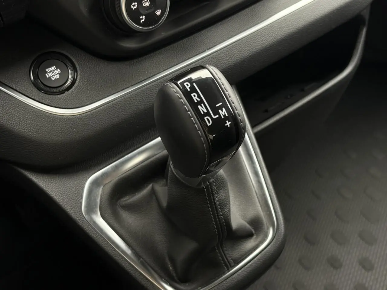 Gros plan sur le levier de vitesses automatique noir du Nissan Primastar 2025, entouré de garniture argentée et bouton start engine stop.