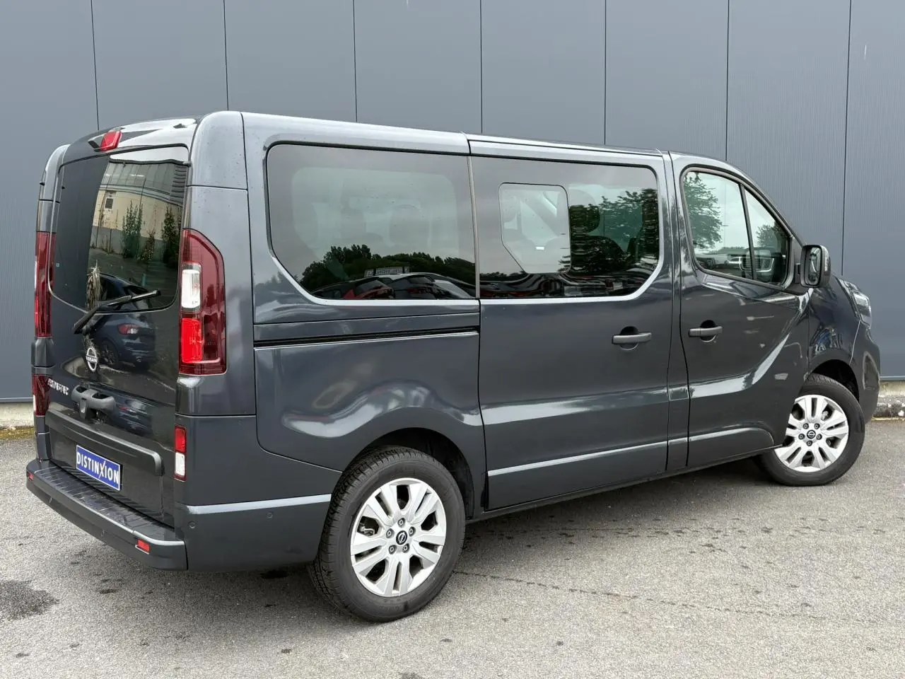 Vue 3/4 arrière droite du Nissan Primastar gris comète avec hayon vitré et jantes alliage 17 pouces.