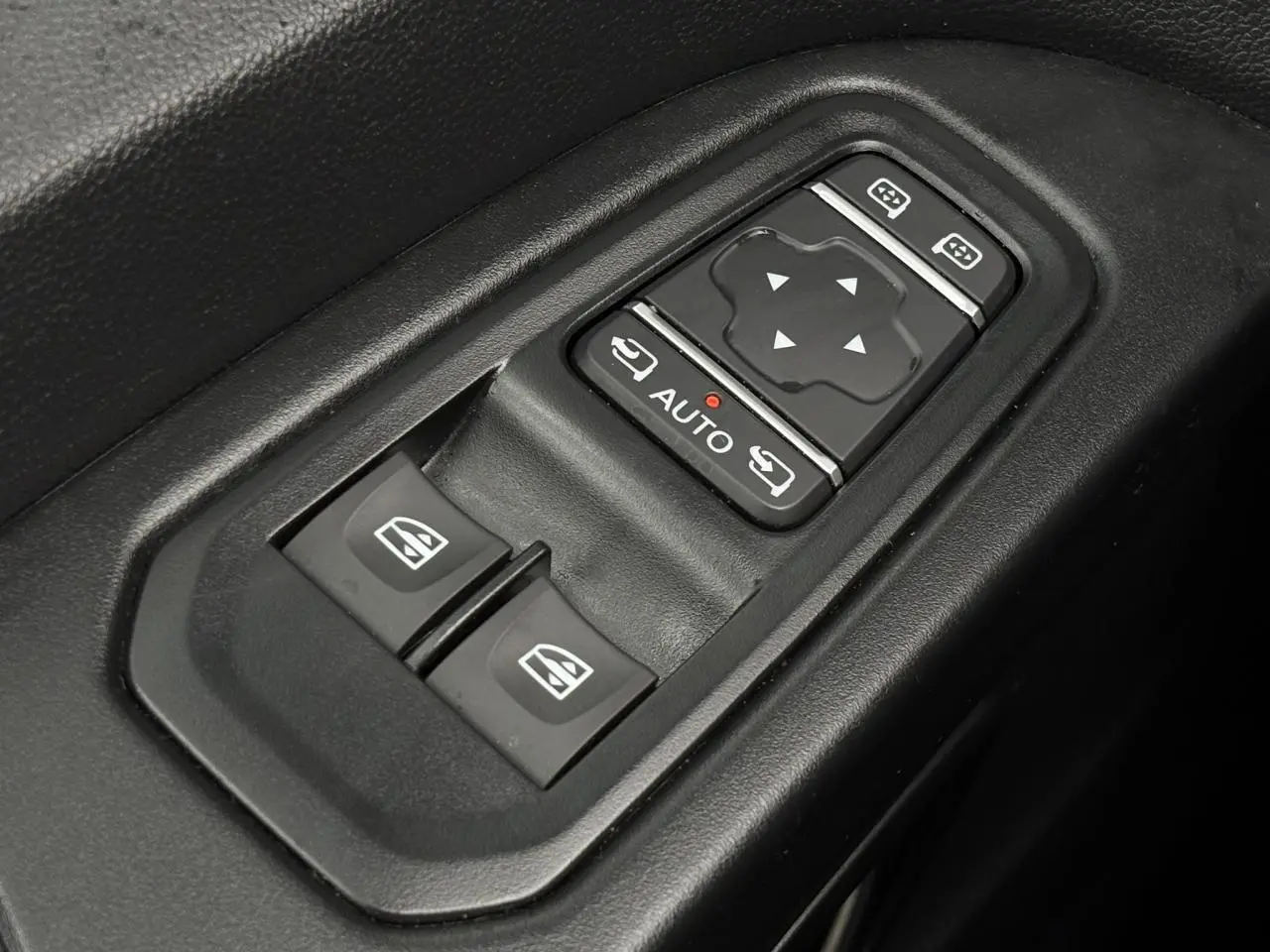 Gros plan sur les commandes de lève-vitres et réglages des rétroviseurs du Nissan Primastar gris Comète, côté conducteur.