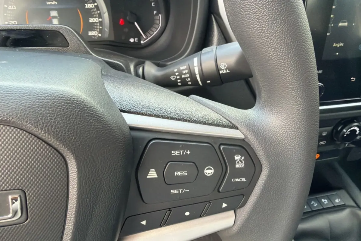 Gros plan sur le volant multifonctions de l'Isuzu D-MAX 2026, avec commandes de régulateur et tableau de bord partiel.