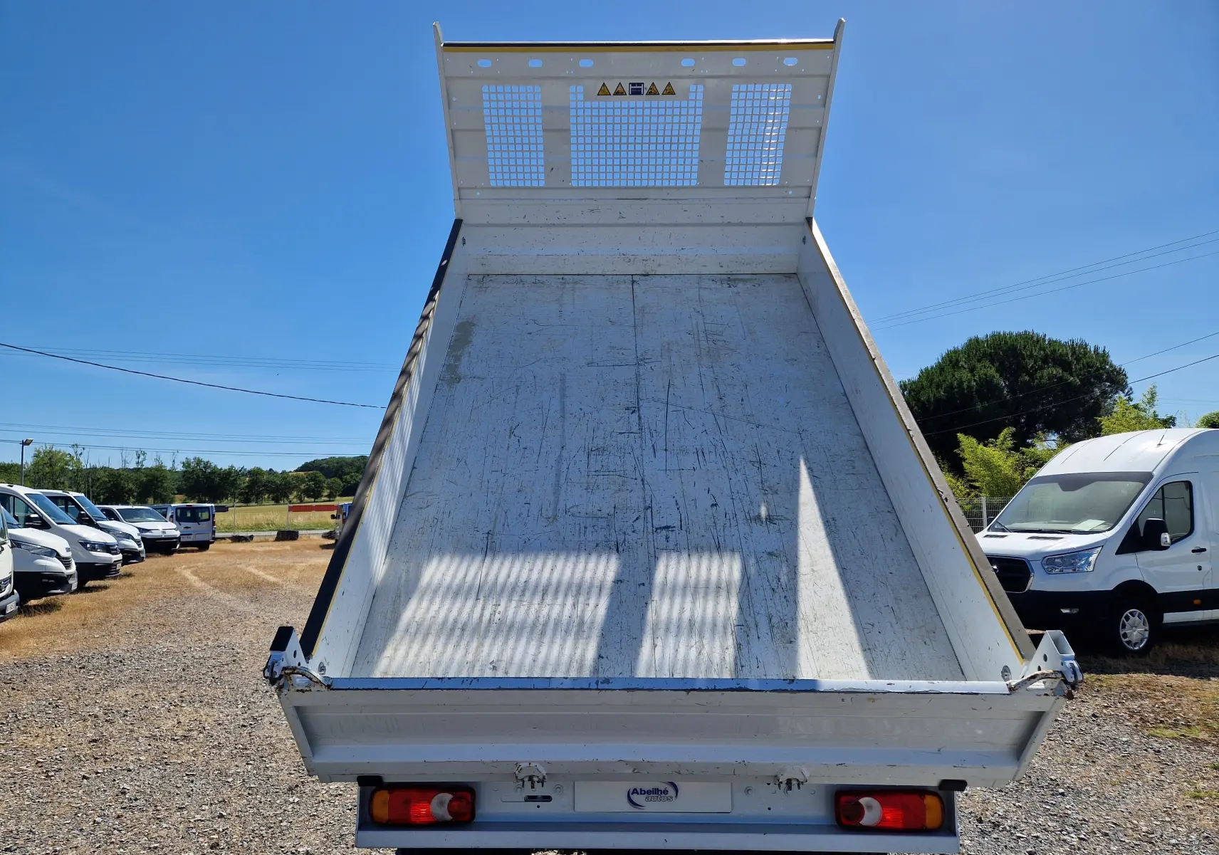 Vue arrière d’une benne relevée blanche sur un Renault Master Châssis Cabine 2024 avec roues jumelées.
