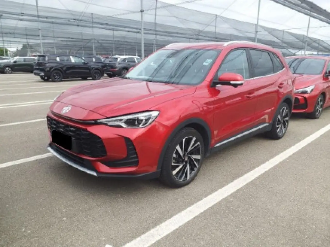 MG ZS 1.5 Hybrid+ 197 Luxury rouge Diamond vu en 3/4 avant droit sur parking extérieur.
