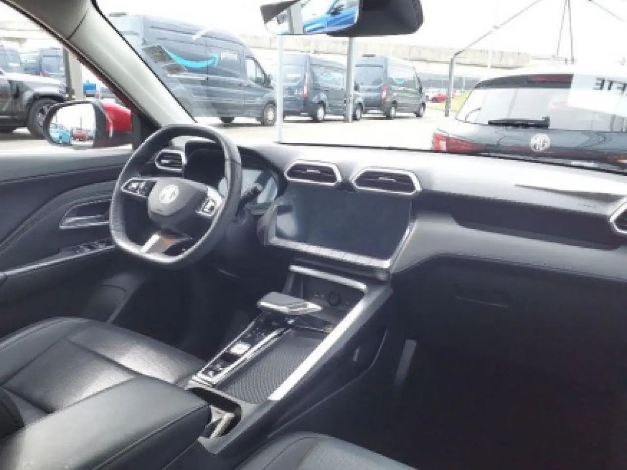 Vue intérieure avant du MG ZS 1.5 Hybrid+ 197 Luxury, tableau de bord noir avec écran tactile et volant cuir.