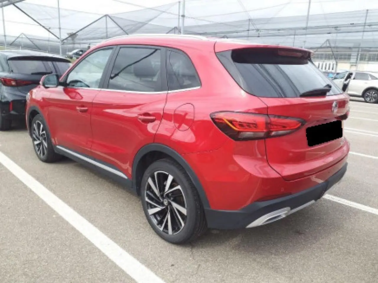 MG ZS 1.5 Hybrid+ 2025 rouge Diamond, vue 3/4 arrière droit, jantes alliage noires et feux arrière LED.