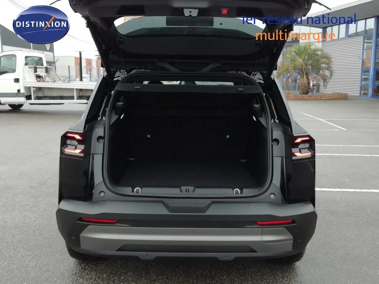 Vue arrière d’un Jeep Compass noir Vulcano métal avec coffre ouvert, feux arrière allumés et pare-chocs gris.