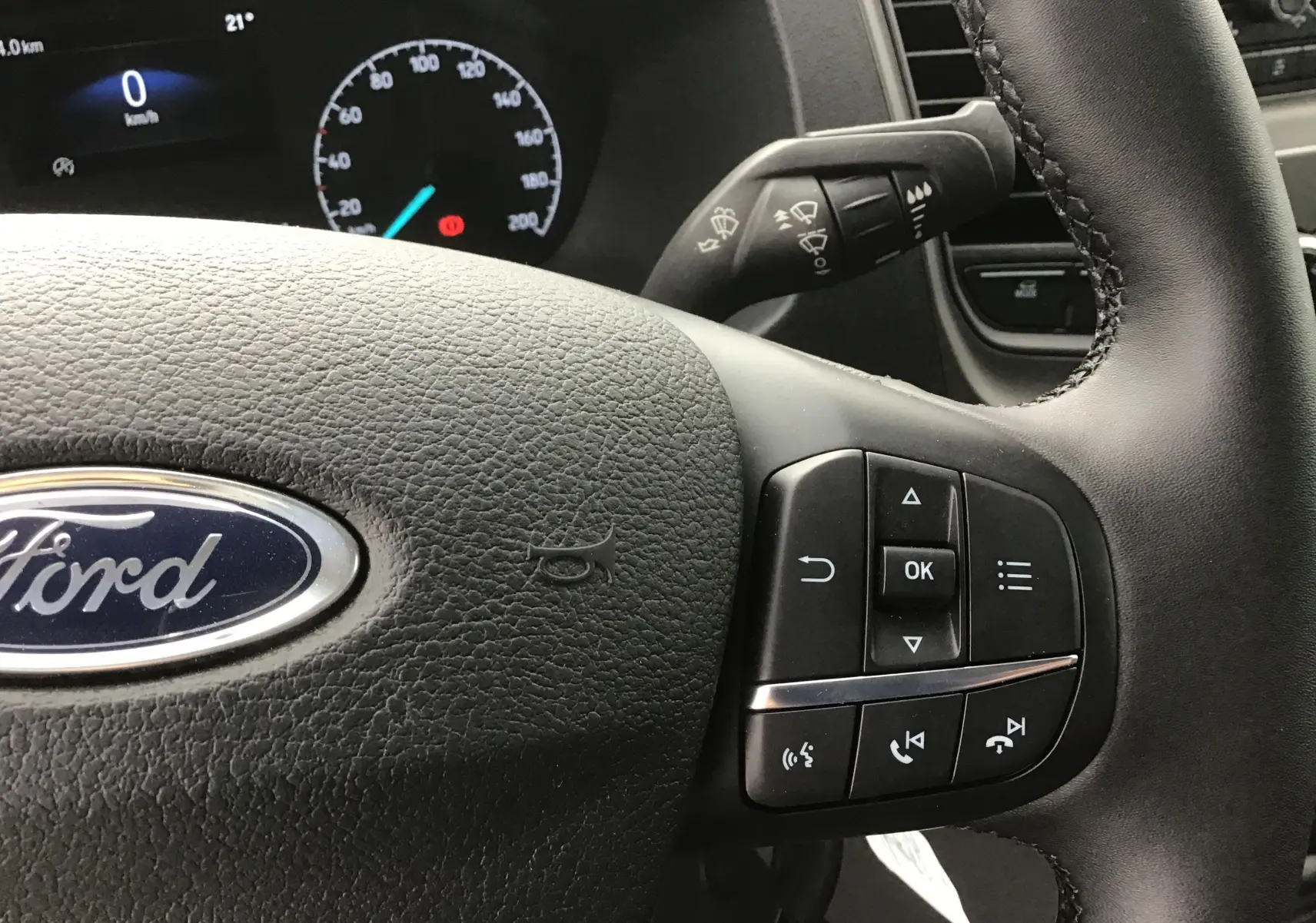 Gros plan sur le volant du Ford Transit Chassis Cabine 2024 avec commandes multifonctions et tableau de bord numérique.