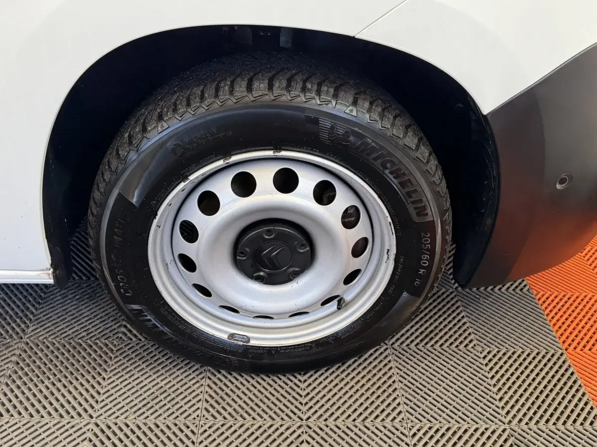 Gros plan sur la roue arrière droite en jante acier argentée du Citroën Berlingo blanc, avec pneu Michelin visible.