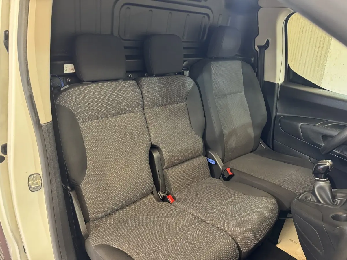 Vue intérieure côté conducteur du Citroën Berlingo blanc 2020, montrant les sièges avant en tissu gris et la boîte manuelle.