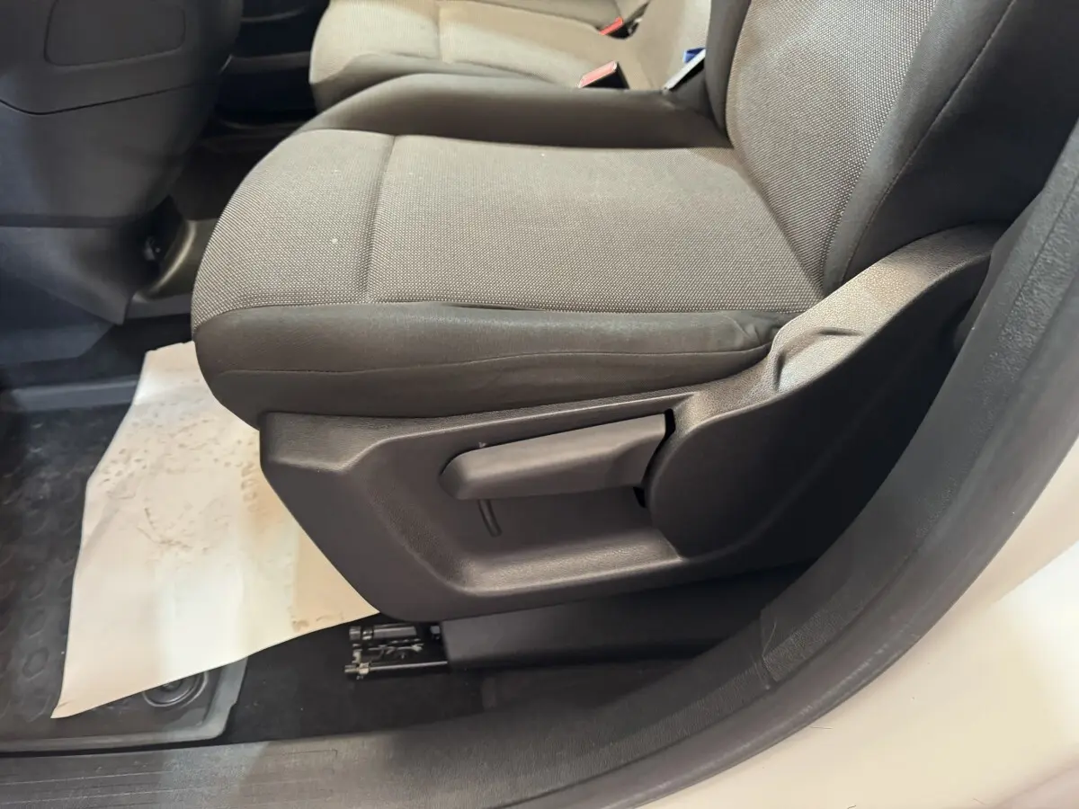 Gros plan sur le siège avant droit gris du Citroën Berlingo blanc, montrant la manette de réglage latérale.