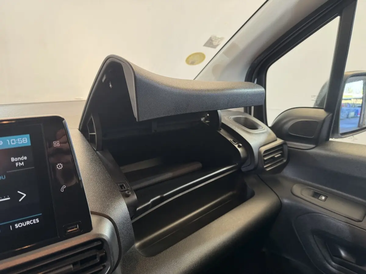 Vue intérieure côté passager du tableau de bord noir du Citroën Berlingo 2020 avec boîte à gants ouverte et écran tactile visible.