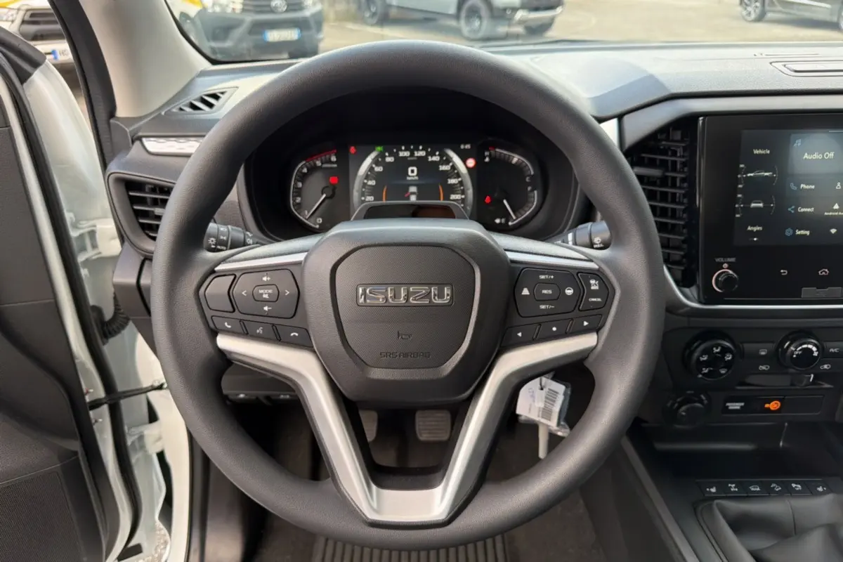 Vue intérieure centrée sur le volant multifonctions noir de l'Isuzu D-MAX 2026 Splash White avec tableau de bord et écran tactile.