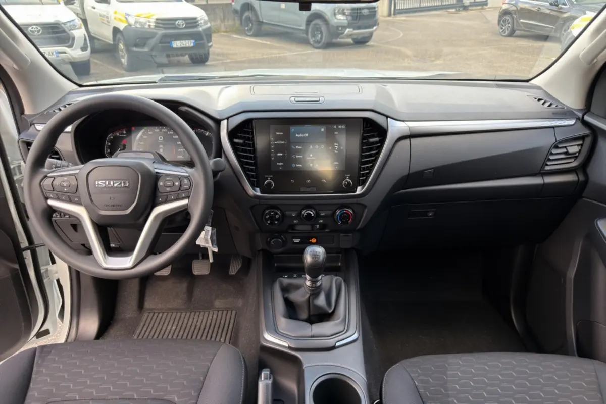 Vue intérieure avant de l'Isuzu D-MAX 2.2 TD 164 Space Evolution avec tableau de bord noir et écran tactile central.