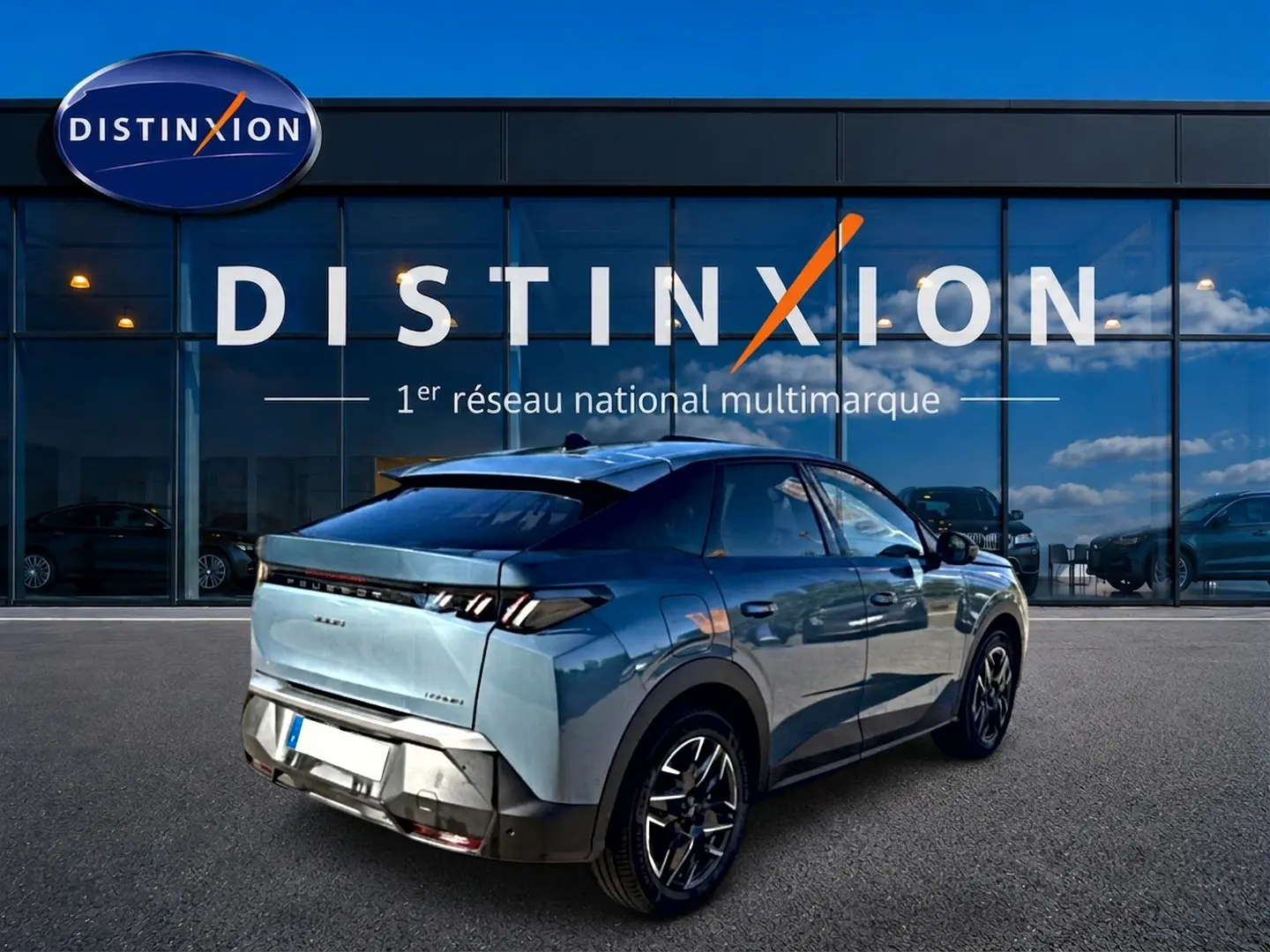 Vue 3/4 arrière droite d’un Peugeot 3008 bleu 2025 avec jantes alu et feux arrière LED, devant un showroom Distinxion.