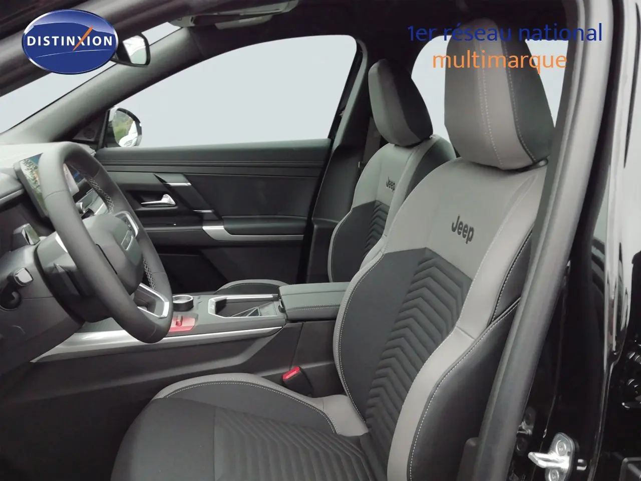 Vue intérieure côté conducteur du Jeep Compass 2026 noir Vulcano, sièges bi-ton gris et noir avec logo Jeep brodé.