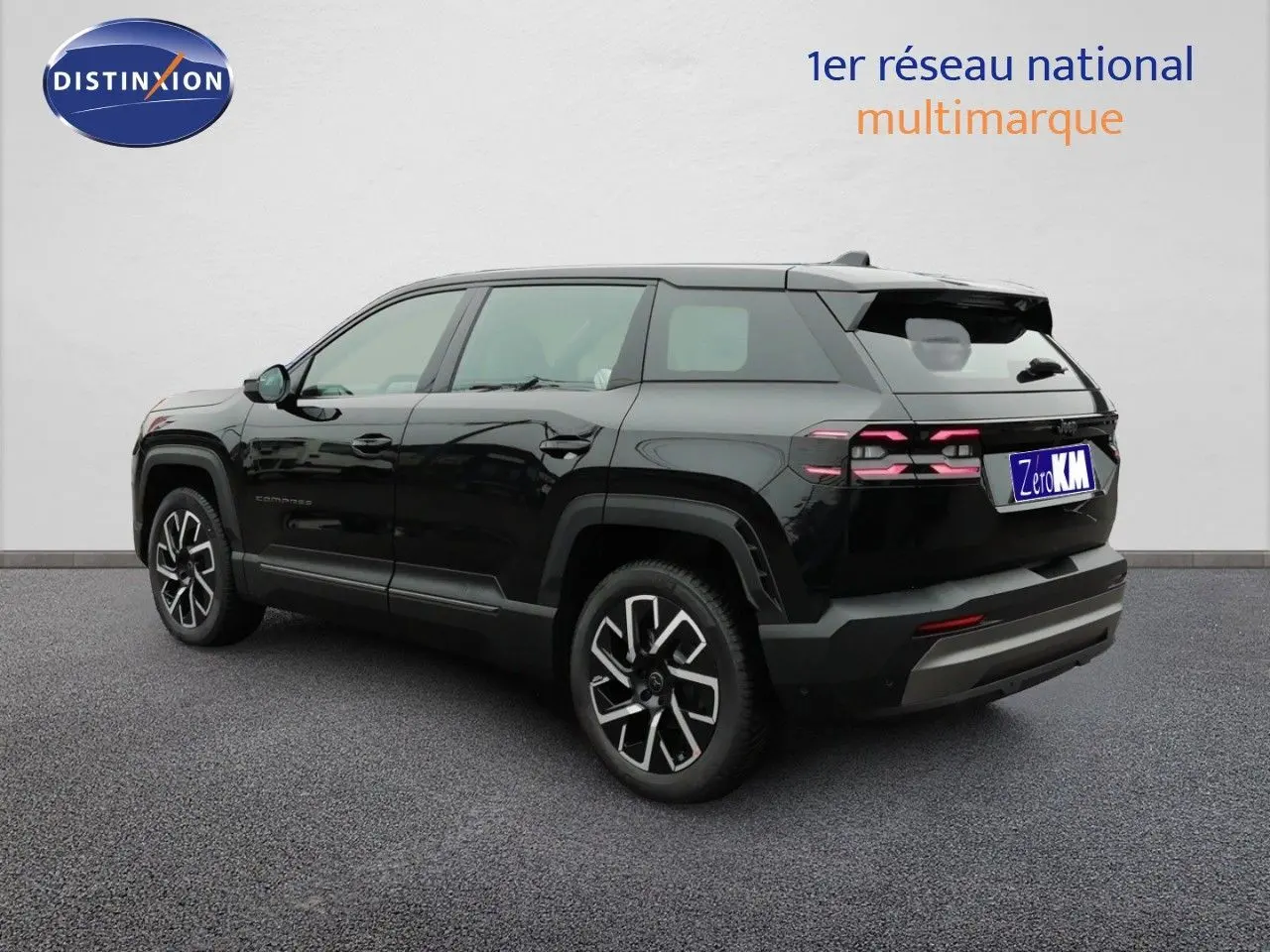 Jeep Compass noir Vulcano métal vu en 3/4 arrière droit, avec jantes alliage distinctives et feux arrière LED allumés.