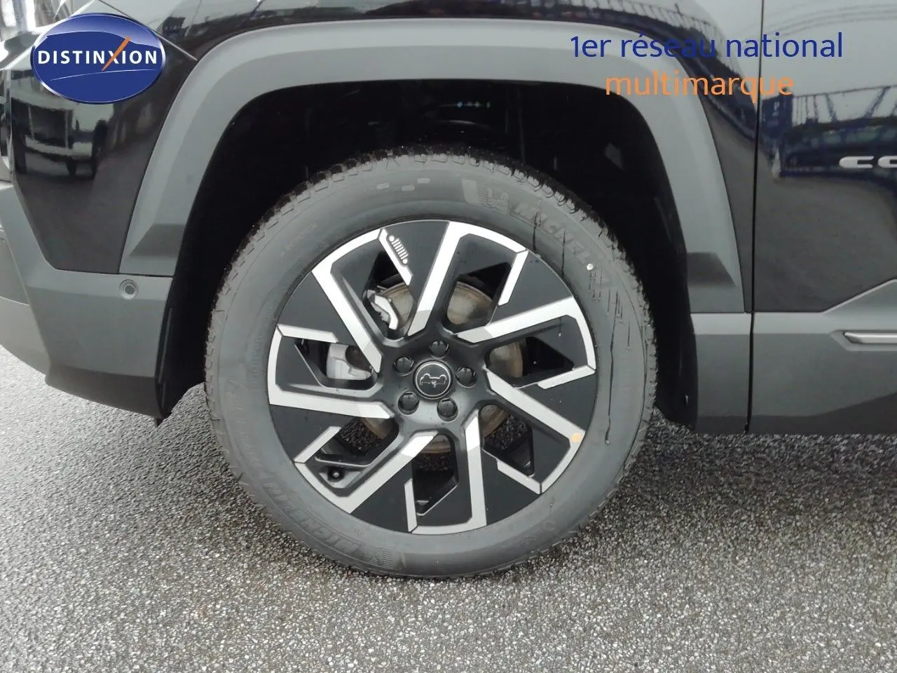 Gros plan sur la roue avant gauche du Jeep Compass noir Vulcano Métal avec jante alliage au design moderne.