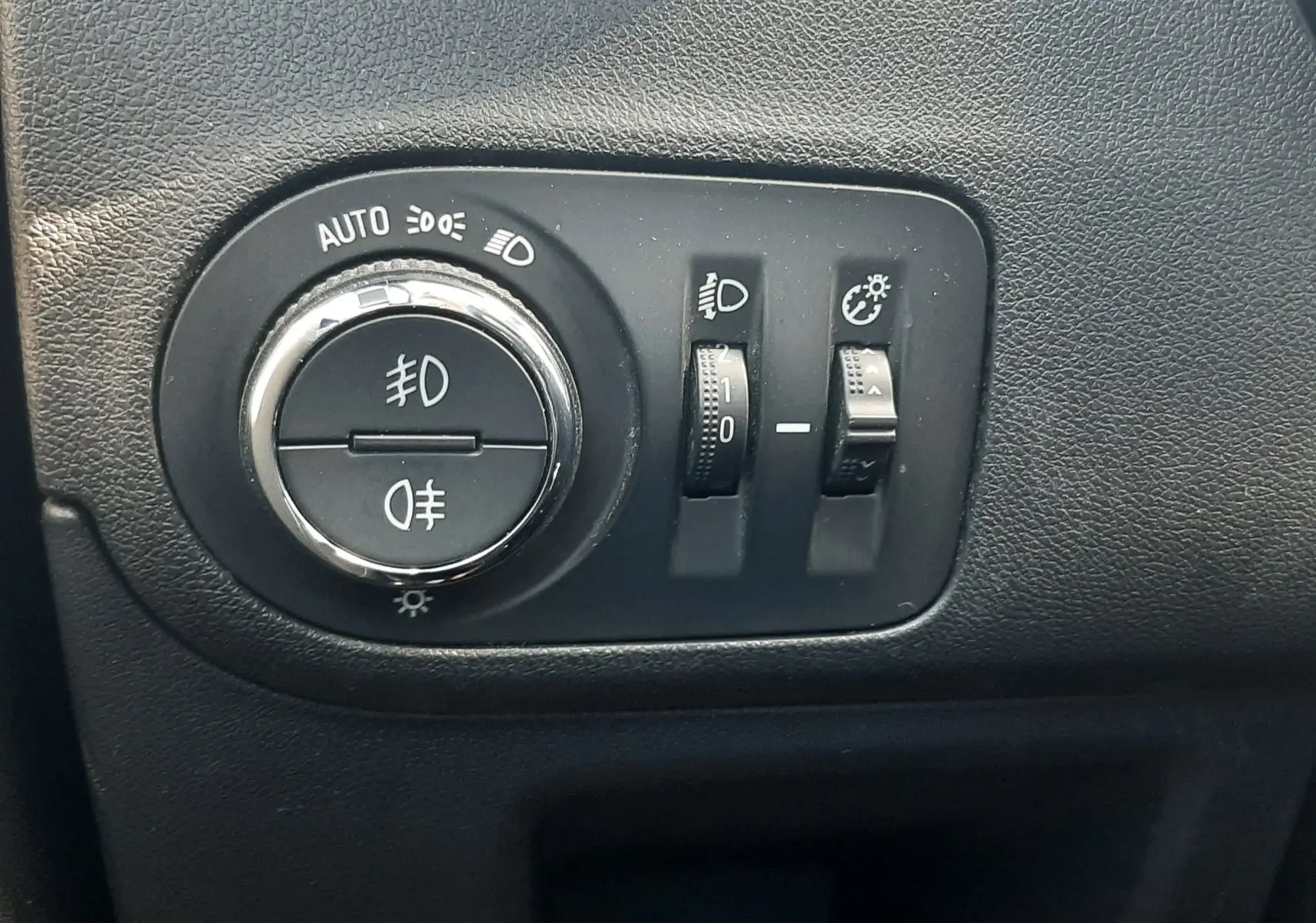 Gros plan sur les commandes d'éclairage noires de l'Opel Crossland X 130ch Innovation 2019, intérieur gris.