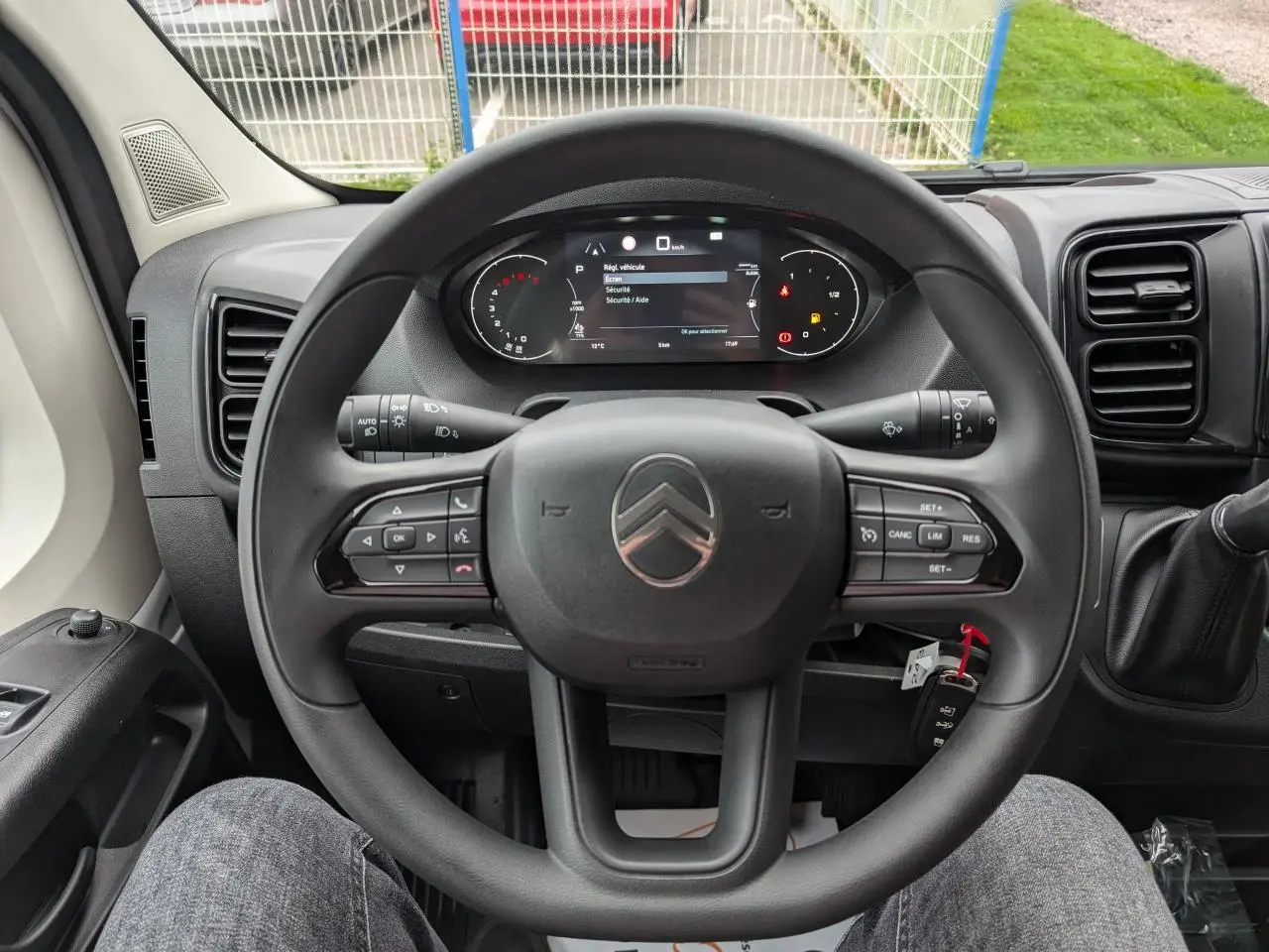 Vue intérieure centrée sur le volant et le combiné numérique du Citroën Jumper blanc 2025, avec clé visible.