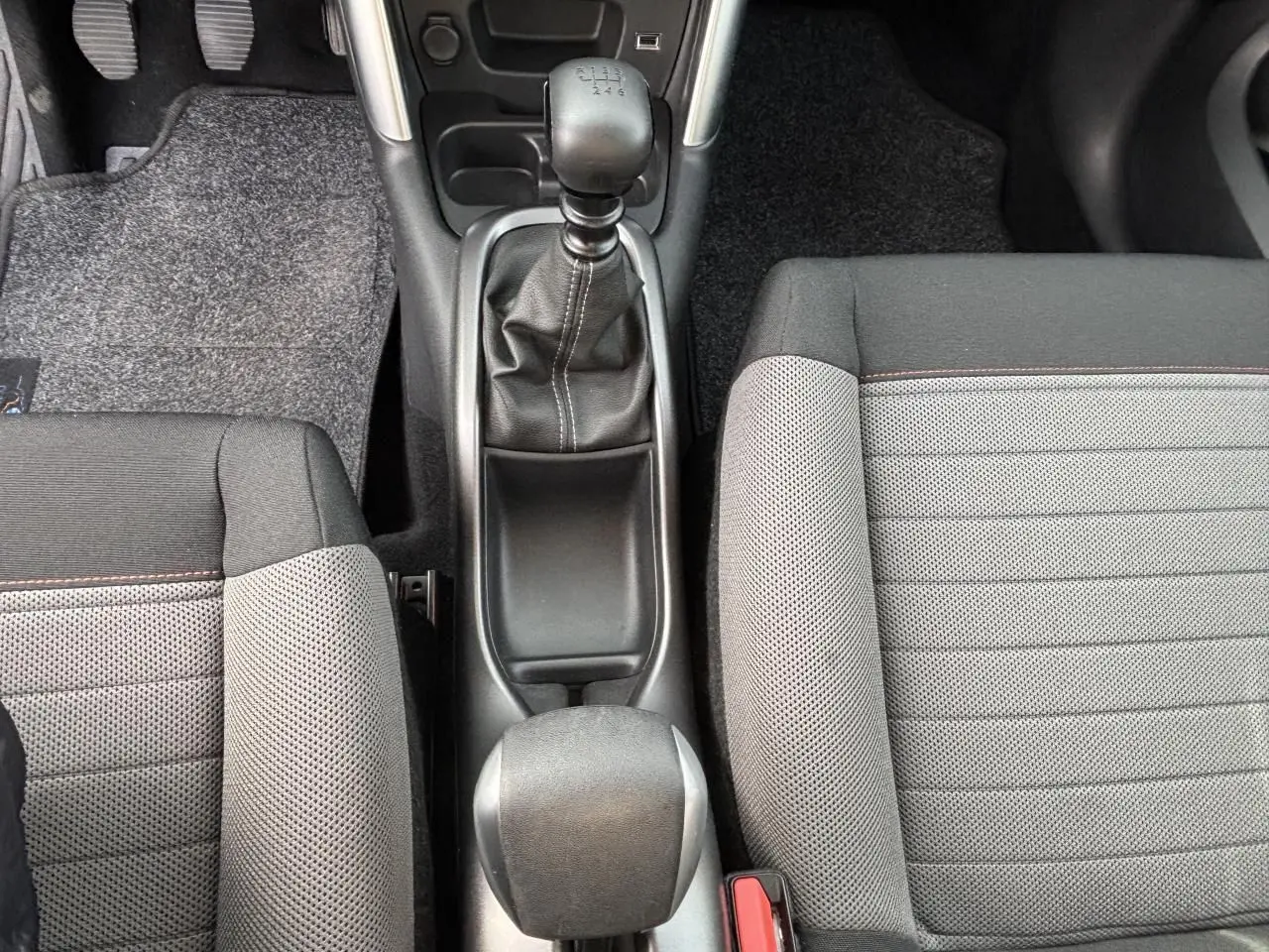 Intérieur avant droit de la Citroën C3 Aircross 2021 avec sièges tissu gris et bande rouge, volant et tableau de bord visibles.