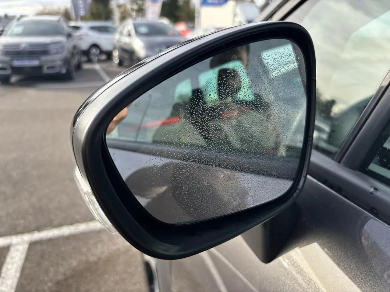 Gros plan sur les commandes des vitres électriques et réglages des rétroviseurs côté conducteur d'une Citroën C3 Aircross gris platinium.