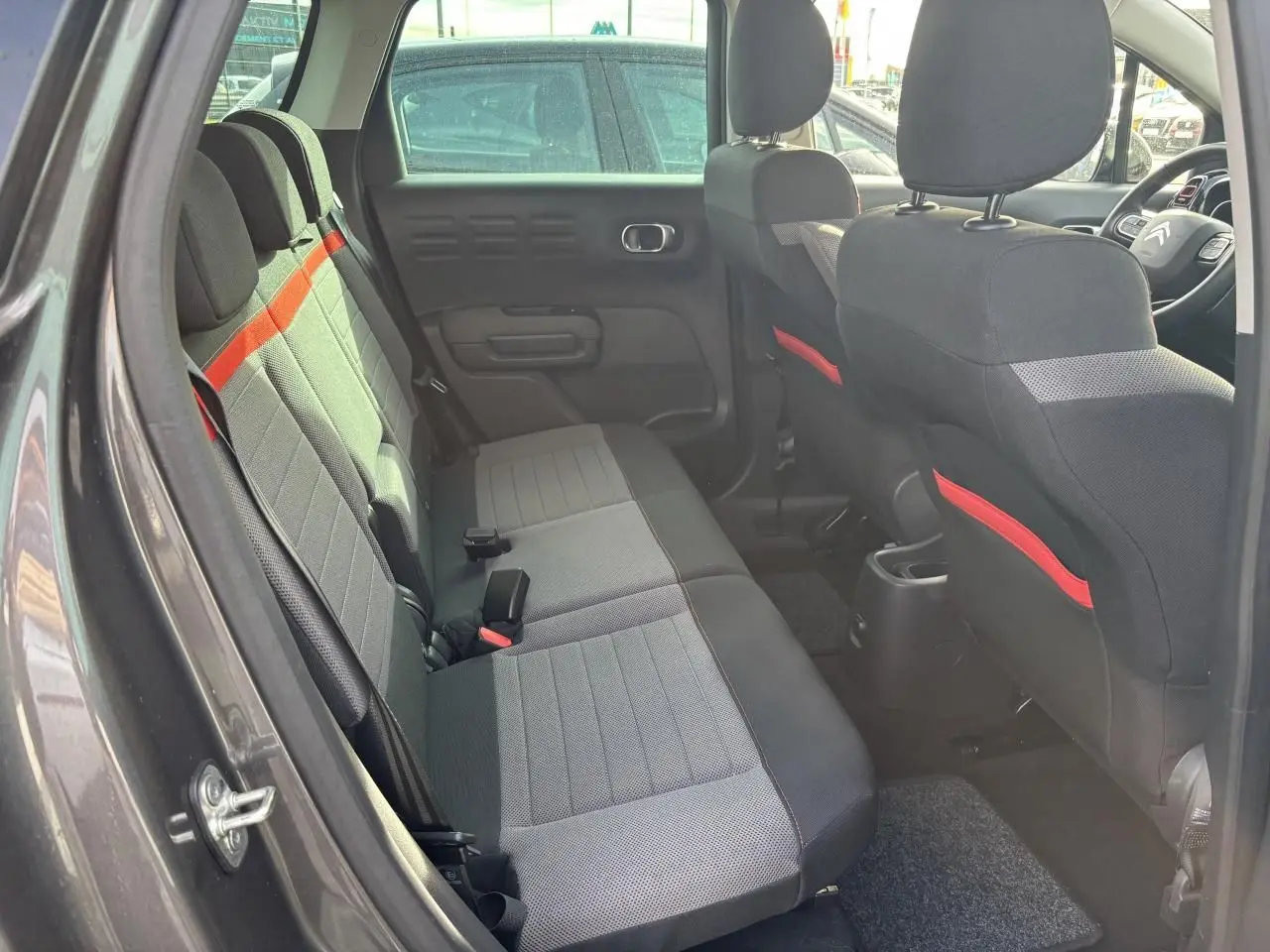 Coffre ouvert vu de l'arrière d'une Citroën C3 Aircross gris platinium avec intérieur noir et banquette rabattue partiellement.