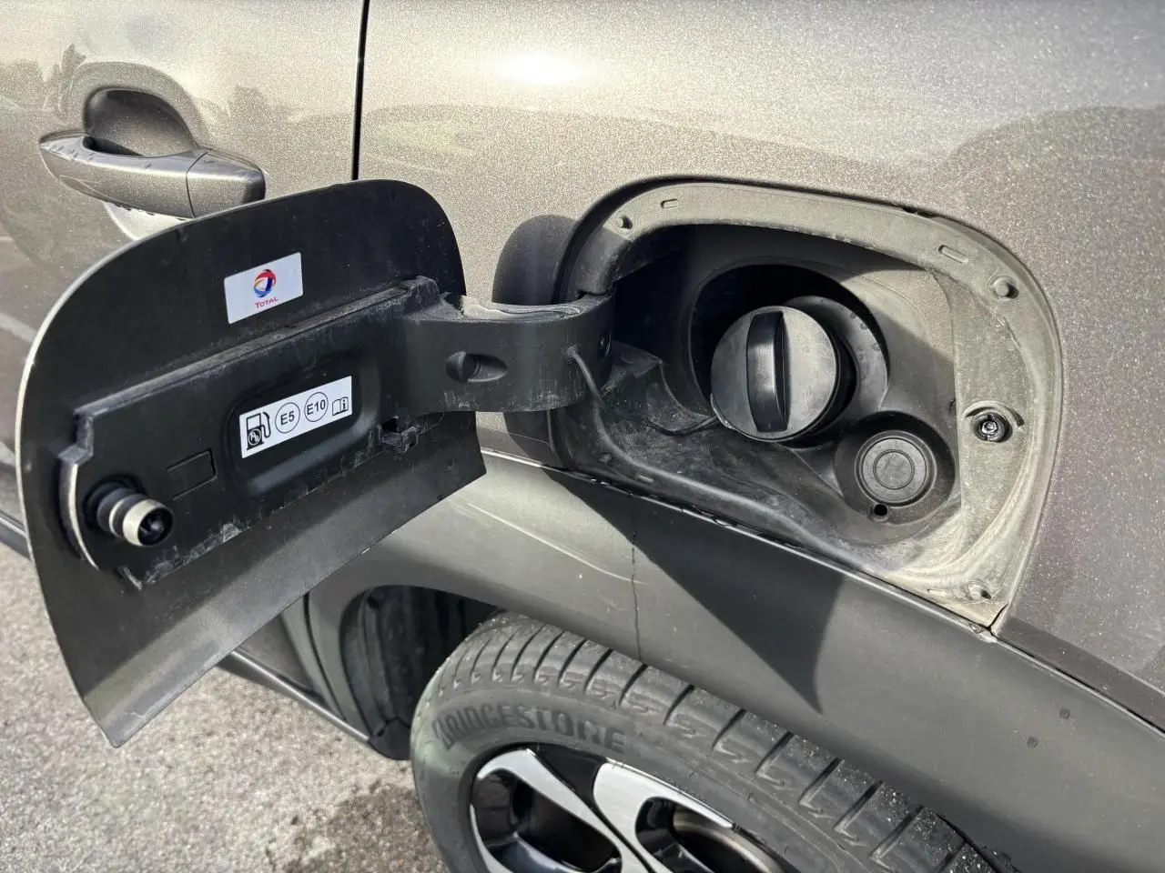 Gros plan sur la trappe à carburant ouverte côté gauche d’un Citroën C3 Aircross gris platinium avec jante alliage 17 pouces.