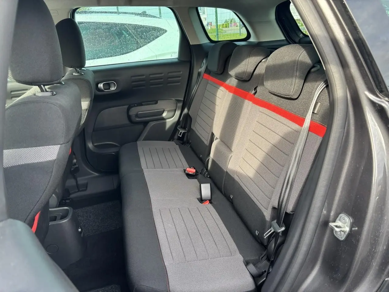 Vue intérieure côté droit sur la banquette arrière grise avec bande rouge du Citroën C3 Aircross 2021.