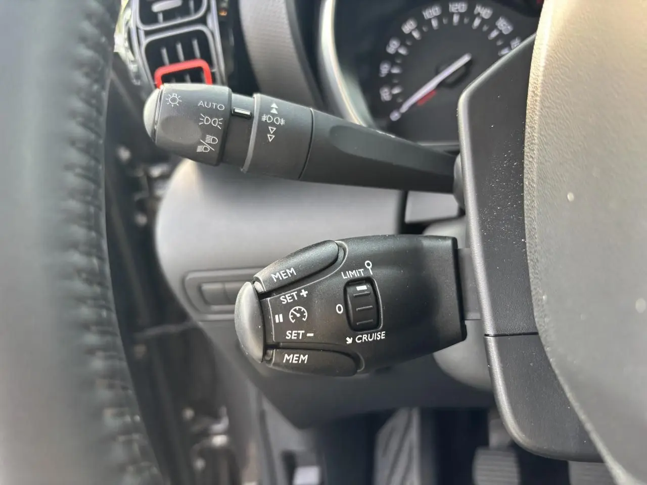Gros plan sur les commandes au volant noir du Citroën C3 Aircross 2021, côté gauche du tableau de bord gris.