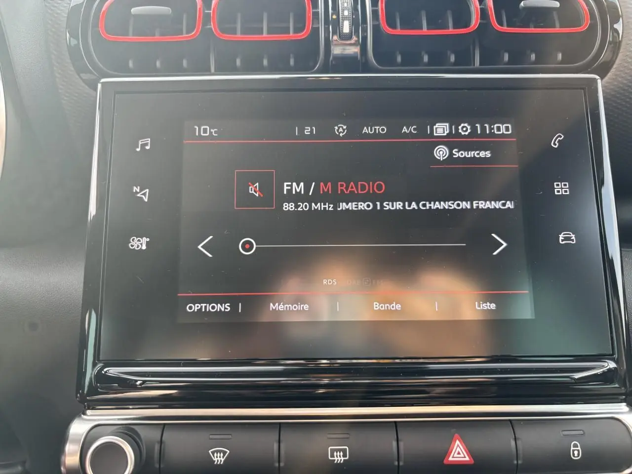 Écran tactile central de la Citroën C3 Aircross 2021 affichant la radio FM, entouré de buses d’aération avec contours rouges.
