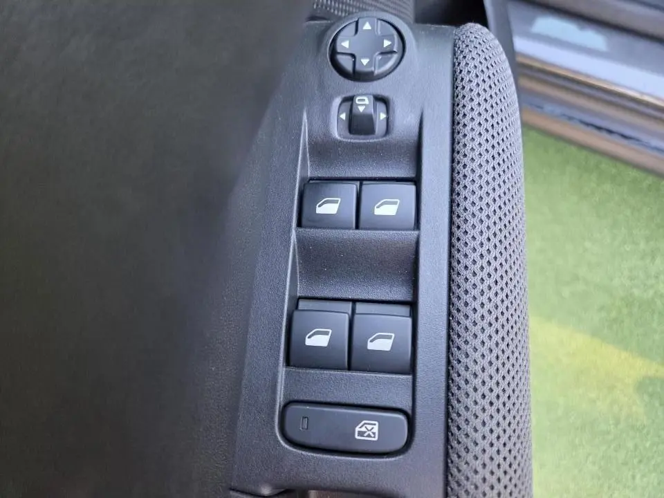 Gros plan sur les commandes de lève-vitres et réglages des rétroviseurs côté conducteur du Citroën C3 Aircross gris.