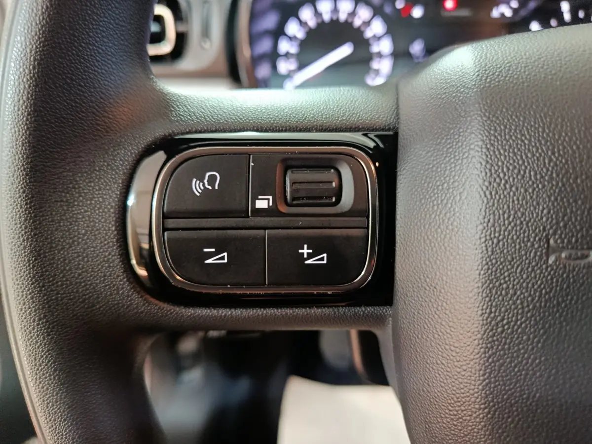 Gros plan sur les commandes de volume et téléphone sur le volant noir de la Citroën C3 2024.