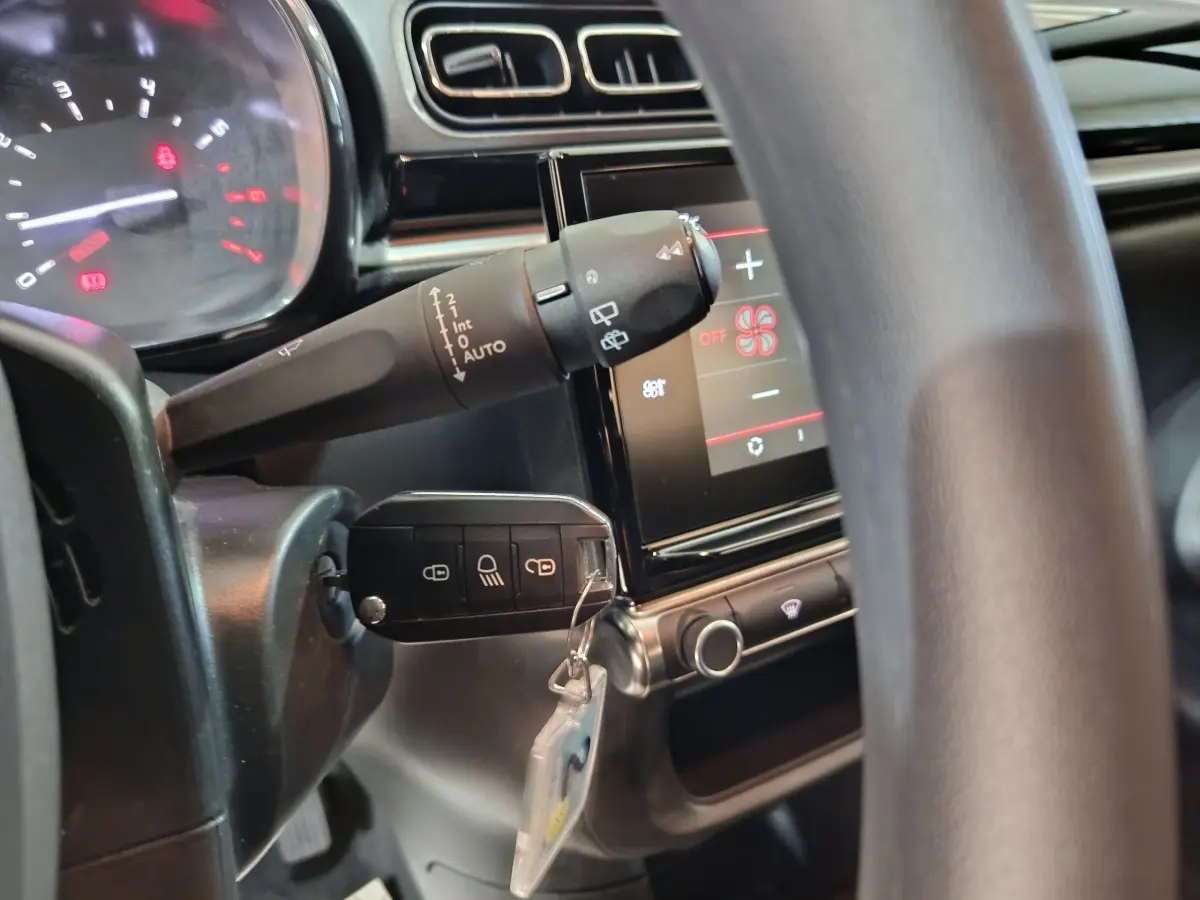 Gros plan intérieur sur la colonne de direction et l'écran tactile d'une Citroën C3 2024 gris foncé.