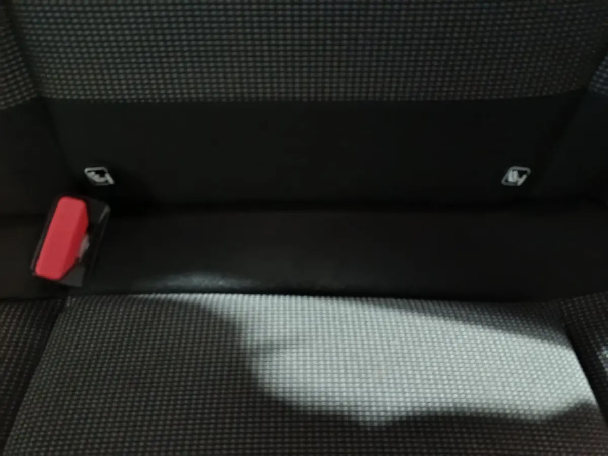 Gros plan sur la banquette arrière gris foncé de la Citroën C3 avec boucle de ceinture rouge visible à gauche.